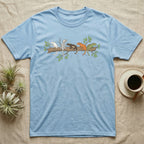 Crested Gecko Morph Line T-Shirt in Light Blue — Five crested gecko morphs in ink and watercolour perched along one cork bark branch with ficus leaves.