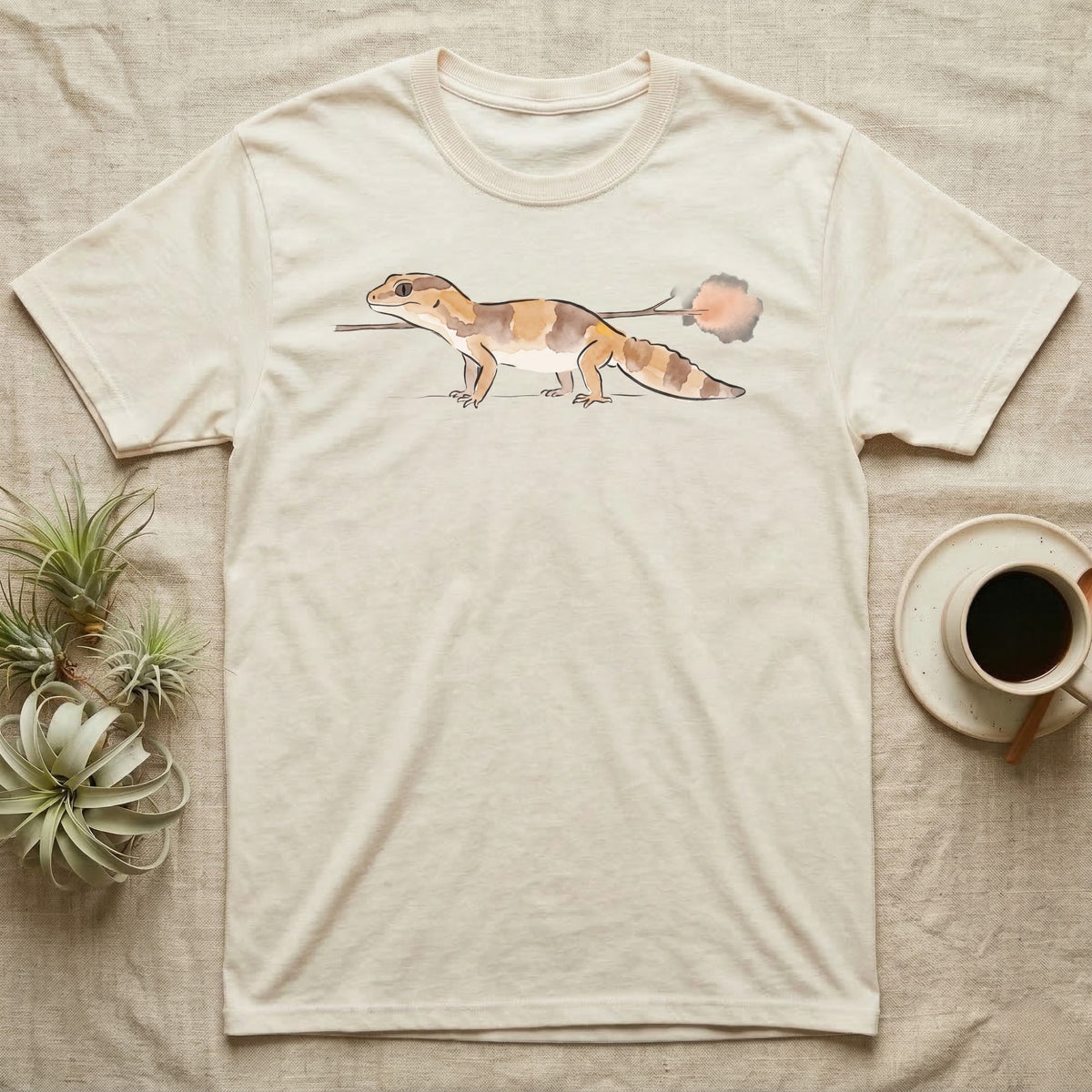 African Fat-Tailed Gecko Watercolour T-Shirt in Natural — Watercolour African fat-tailed gecko in profile beneath a thin twig ending in a soft bloom, drawn with a broken ink line.