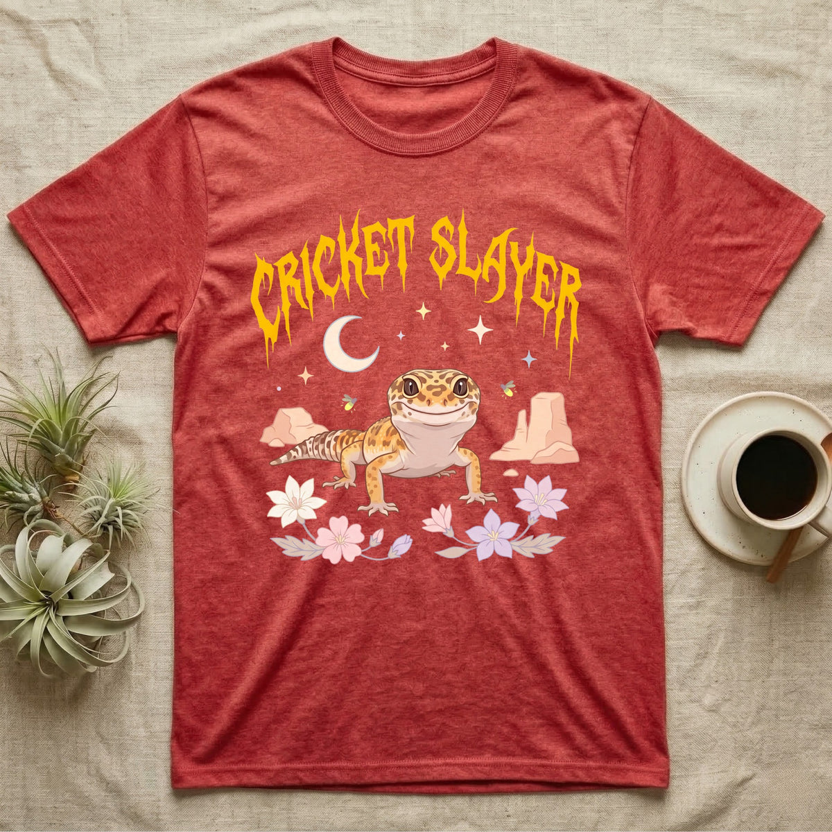 Leopard Gecko Feral T-Shirt in Heather Red — Smiling leopard gecko in a pastel desert-night scene under a spiky golden metal wordmark reading CRICKET SLAYER.