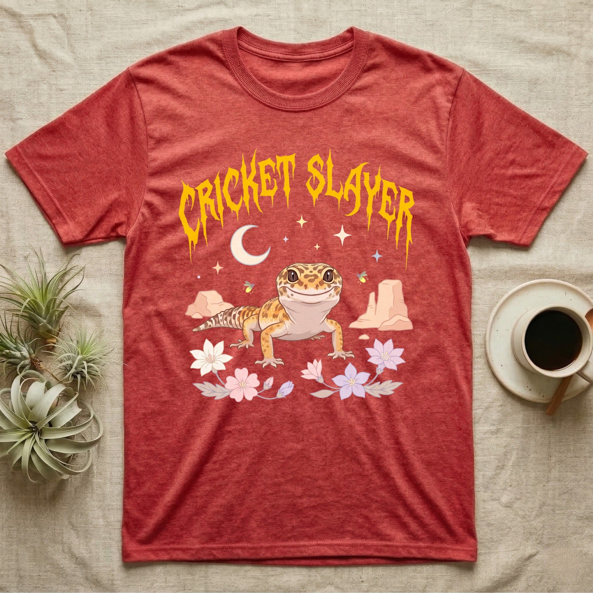Leopard Gecko Feral T-Shirt in Heather Red — Smiling leopard gecko in a pastel desert-night scene under a spiky golden metal wordmark reading CRICKET SLAYER.