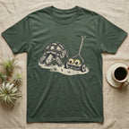 Tortoise Lawnmower Googly T-Shirt in Military Green — Linocut illustration of a sulcata tortoise grazing beside a push mower wearing oversized googly eyes.