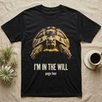 Flat-black mug-shot portrait of a Hermann's tortoise peering from its domed shell, with the printed words I'm In The Will, page four. — shown on a Black tee.