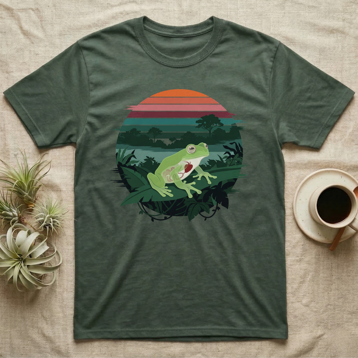 Glass Frog See-Through T-Shirt in Military Green — Flat-colour circle-window illustration of a glass frog silhouetted crossing a rainforest canopy scene.