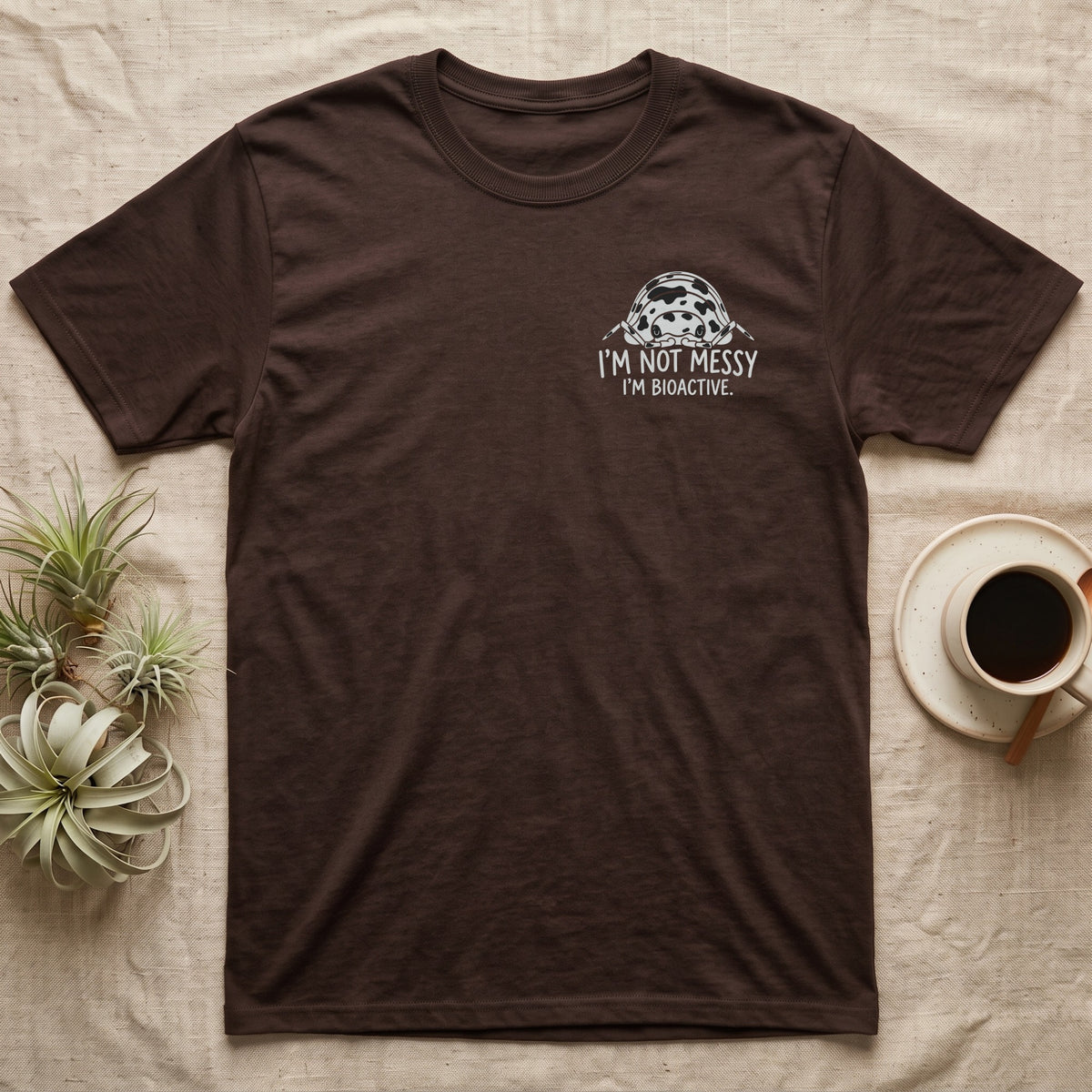 Bioactive Dairy Cow T-Shirt in Dark Chocolate — White dairy cow isopod with black cow patches peeking over white marker capitals reading I'M NOT MESSY I'M BIOACTIVE.