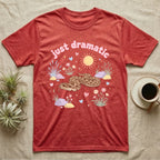 Western Hognose Snake Baby T-Shirt in Heather Red — Pastel western hognose snake in a low coil with tongue out among grasses, puffy pink bubble wordmark "just dramatic" above.