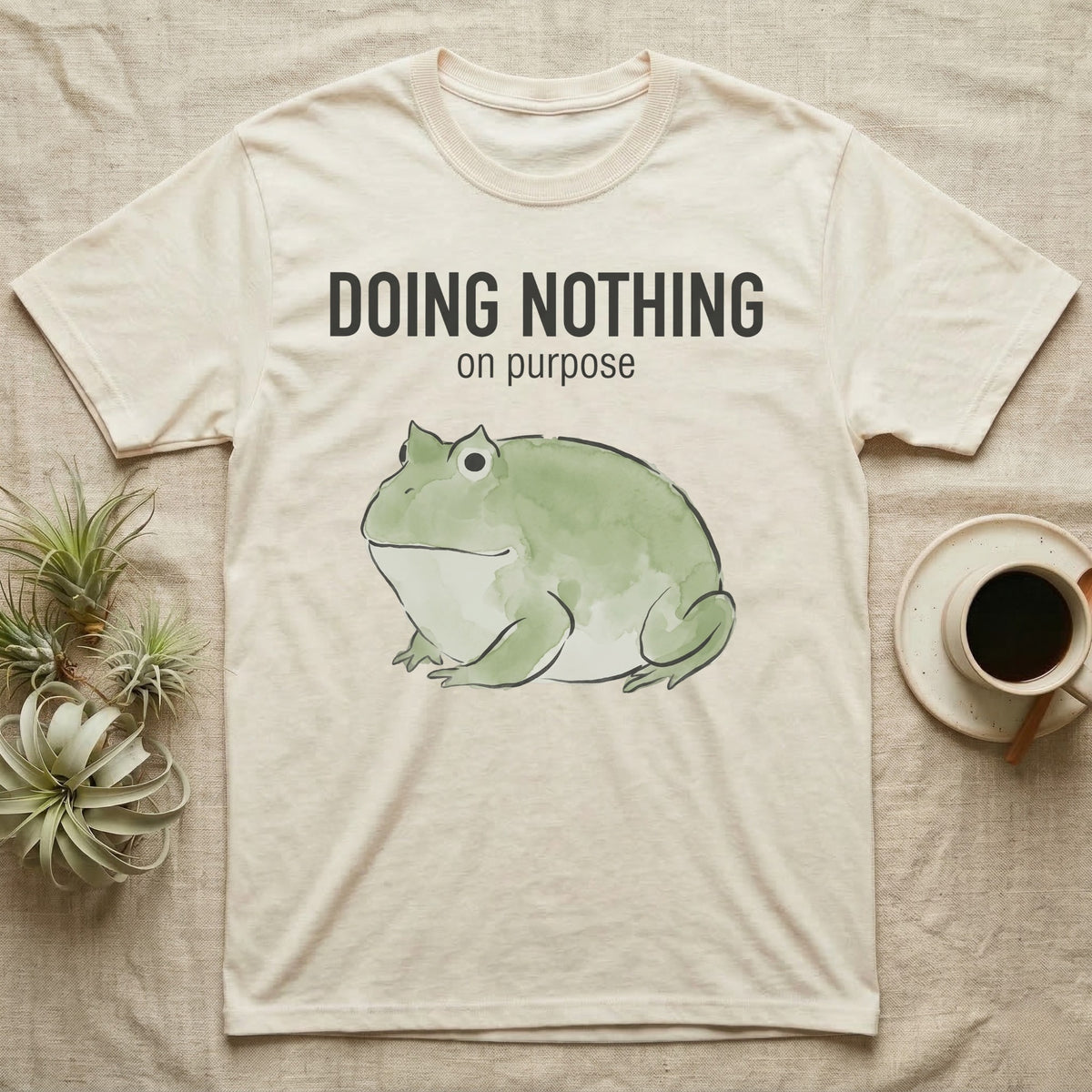 Pacman Frog Doing Nothing T-Shirt in Natural — Watercolour pacman frog blob in profile below the words doing nothing on purpose, on grey