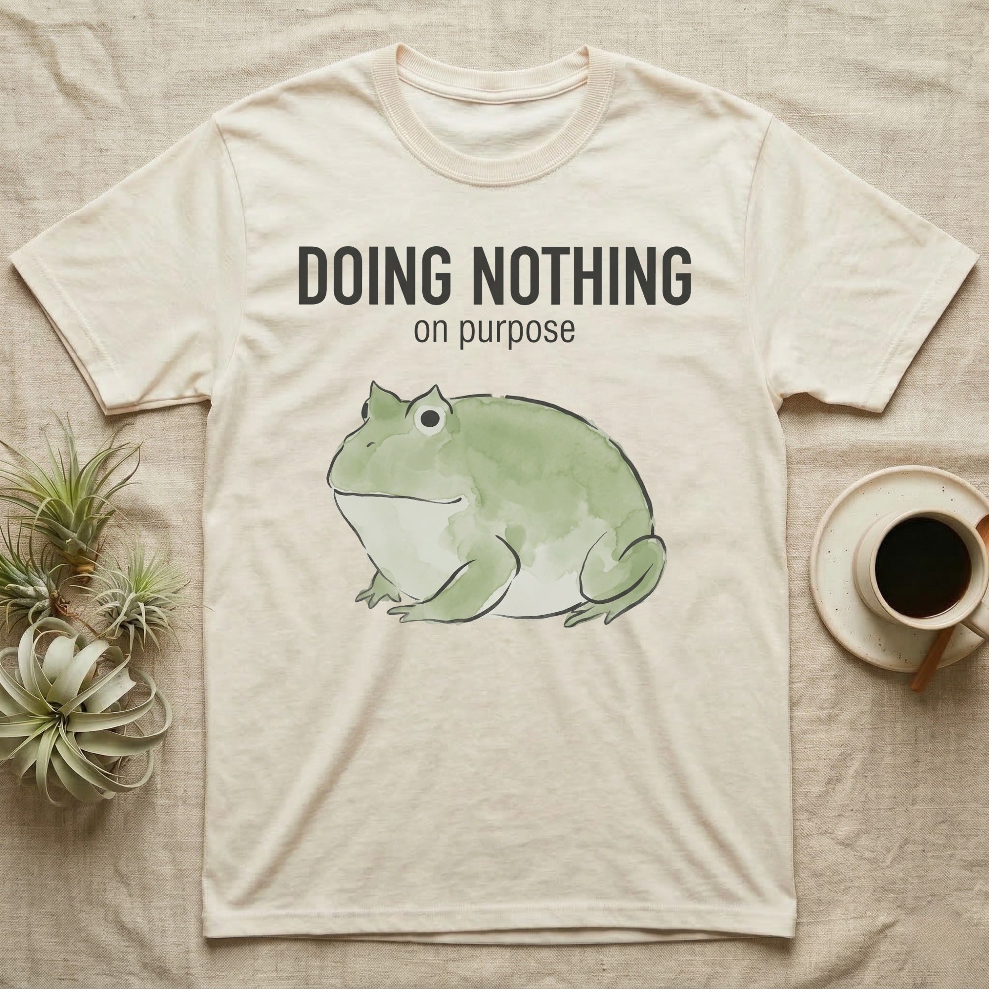 Pacman Frog Doing Nothing T-Shirt in Natural — Watercolour pacman frog blob in profile below the words doing nothing on purpose, on grey