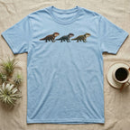 Crocodile Skink Morph Triptych T-Shirt in Light Blue — Three red-eyed crocodile skinks in a row, painted in thick impasto — bronze, near-black and pale olive forms.