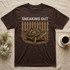 Box Turtle Sneaking T-Shirt in Dark Chocolate — Eastern box turtle crawling out from under a brown picket fence beneath the words Sneaking Out