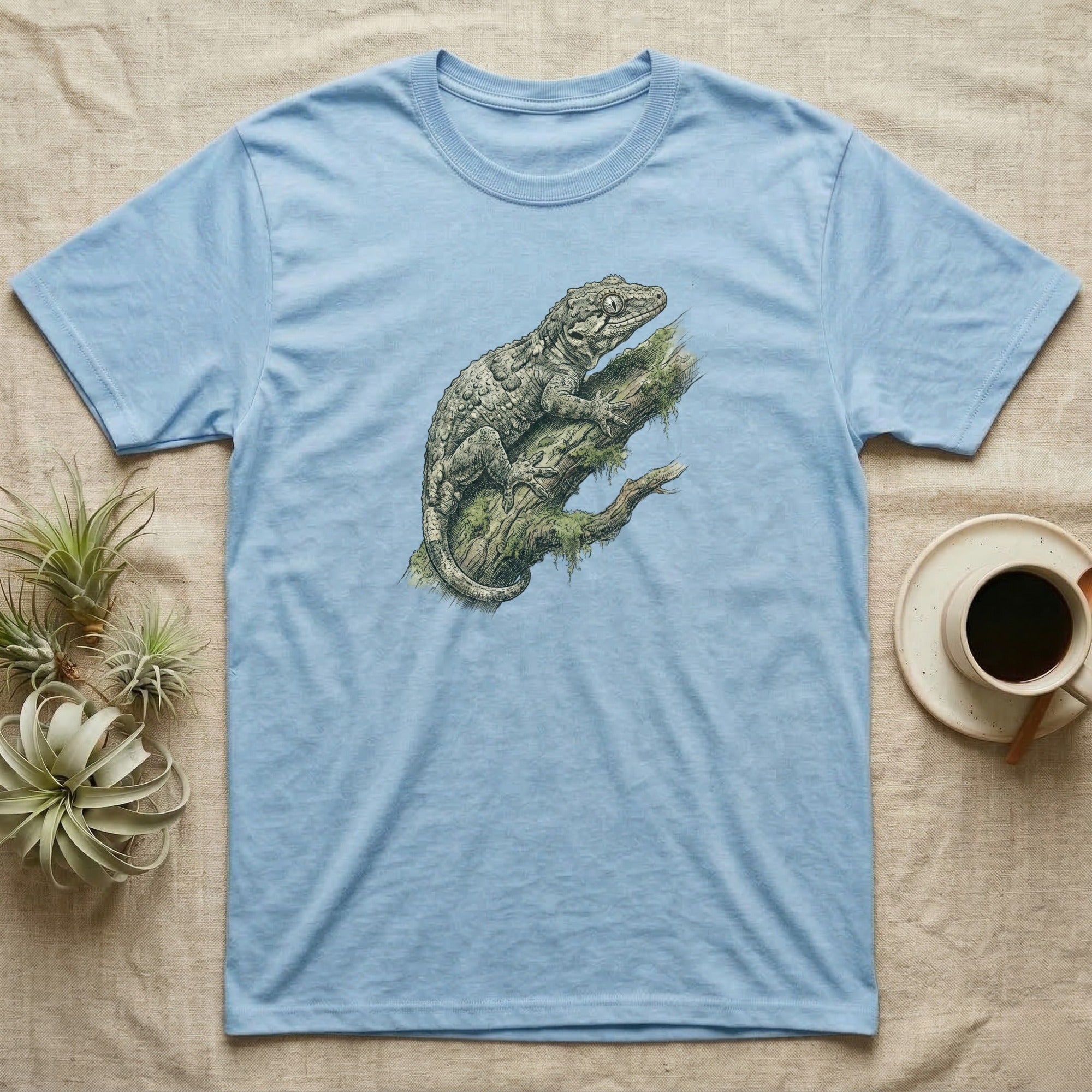Light blue t-shirt with a detailed illustration of a gecko on a mossy branch.