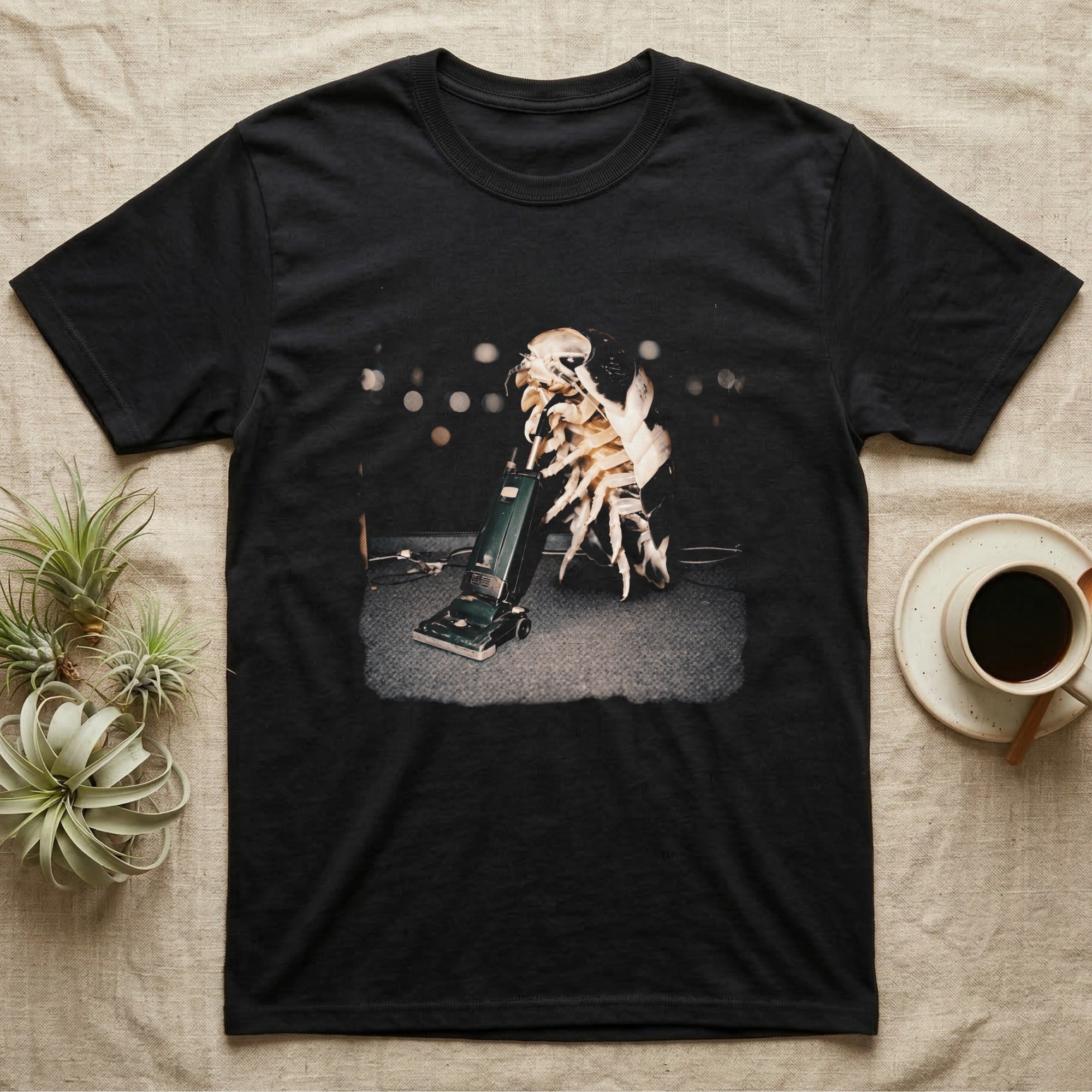 Panda King Isopod Vacuum T-Shirt in Black — Panda King isopod standing upright holding the handle of a vintage upright vacuum cleaner on carpet.