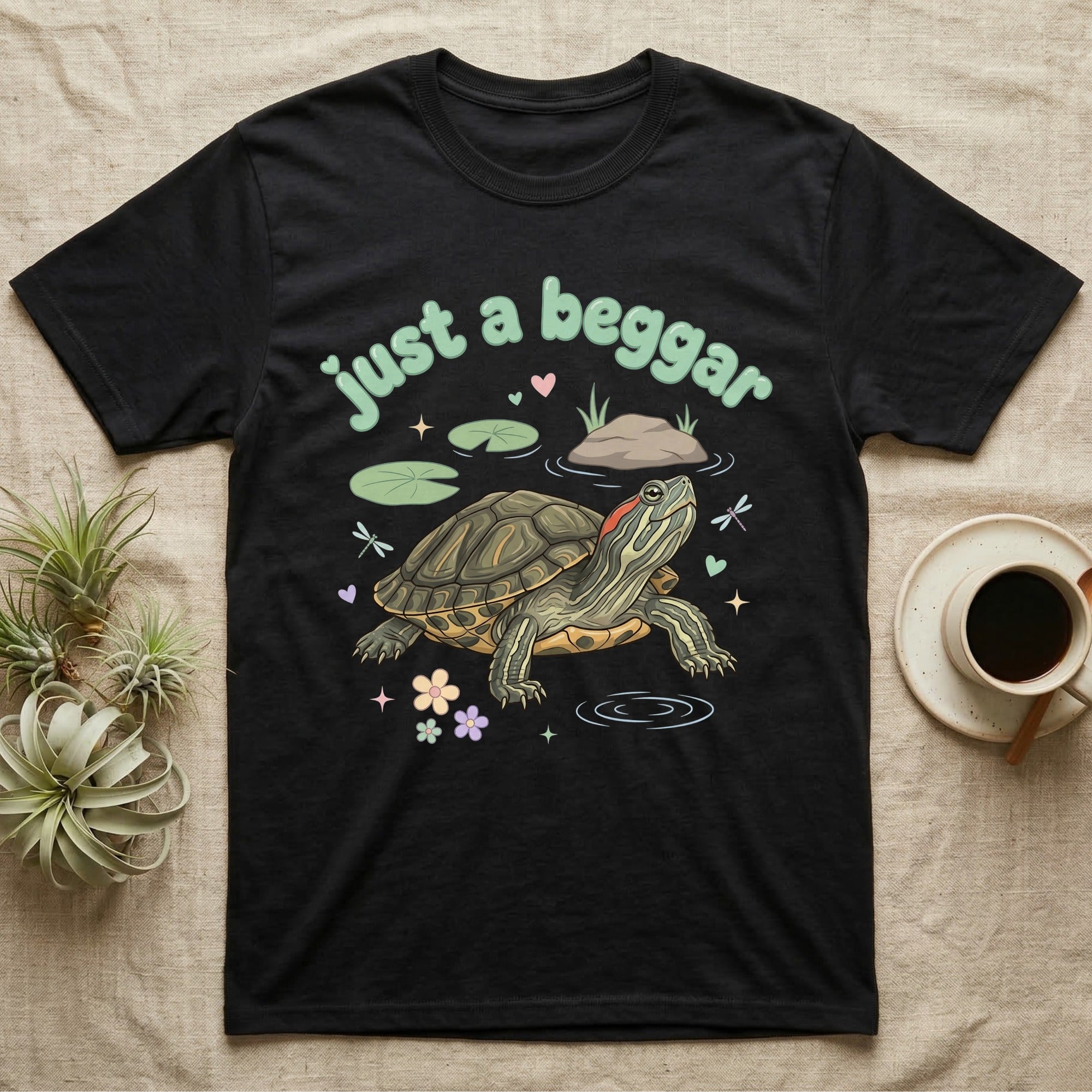 Red-Eared Slider Softie T-Shirt in Black — Red-eared slider turtle stretching its neck to beg, under pastel bubble text "just a beggar" with hearts.