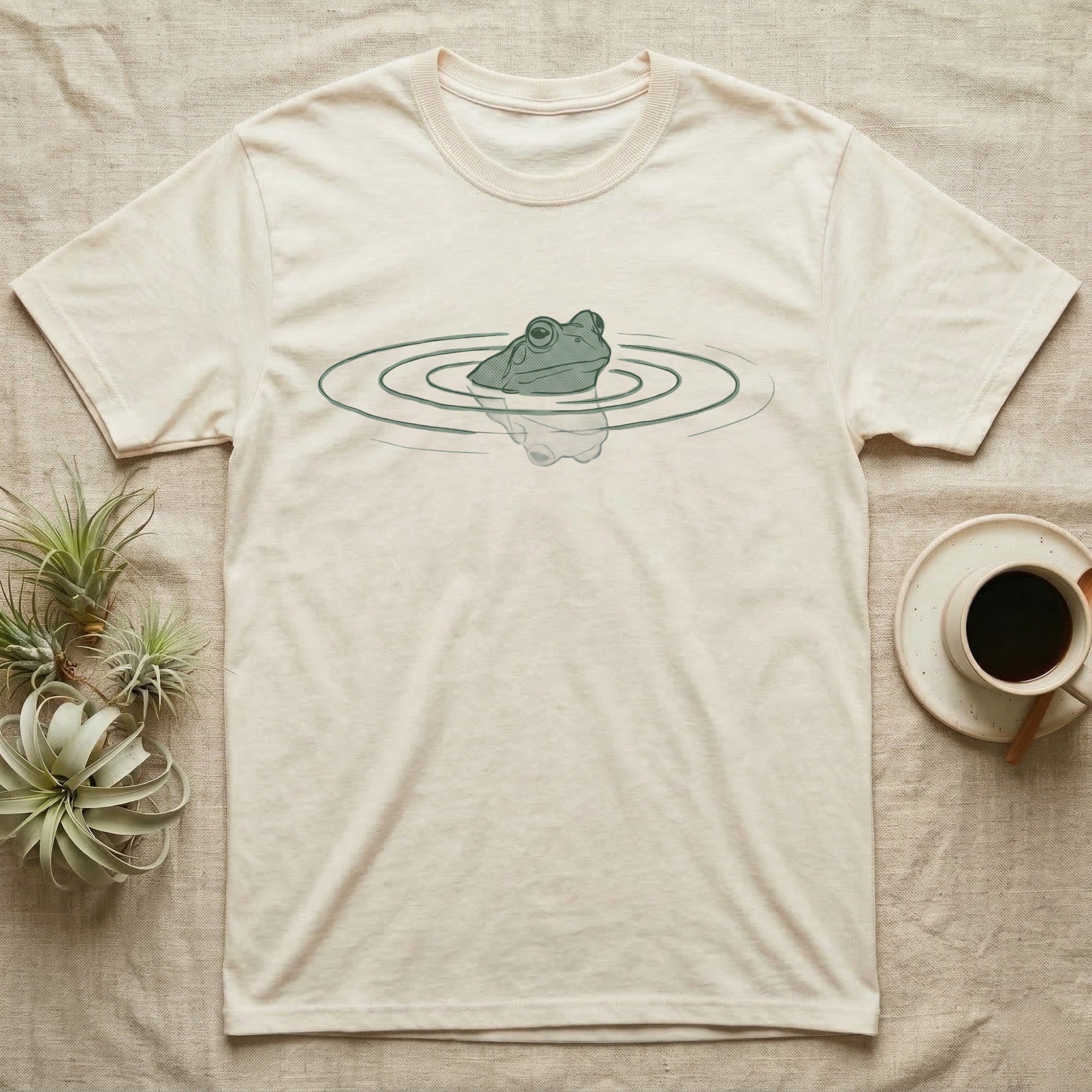 Minimal Swimming Frog T-Shirt in Natural — Minimal single-line illustration of a frog at the waterline with concentric ripple rings and vast negative space.