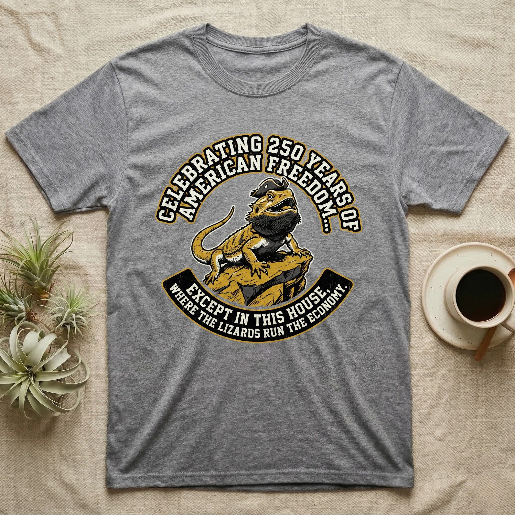 Bearded Dragon 1776 T-Shirt in Sport Grey — Bold woodcut tee of a bearded dragon in a tricorn hat black-bearding on a rock, gold and cream banner reading the lizards run the economy.