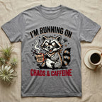 Gray t-shirt with a raccoon holding a mug labeled "Chaos Fuel" and text "I'm Running on Chaos & Caffeine."