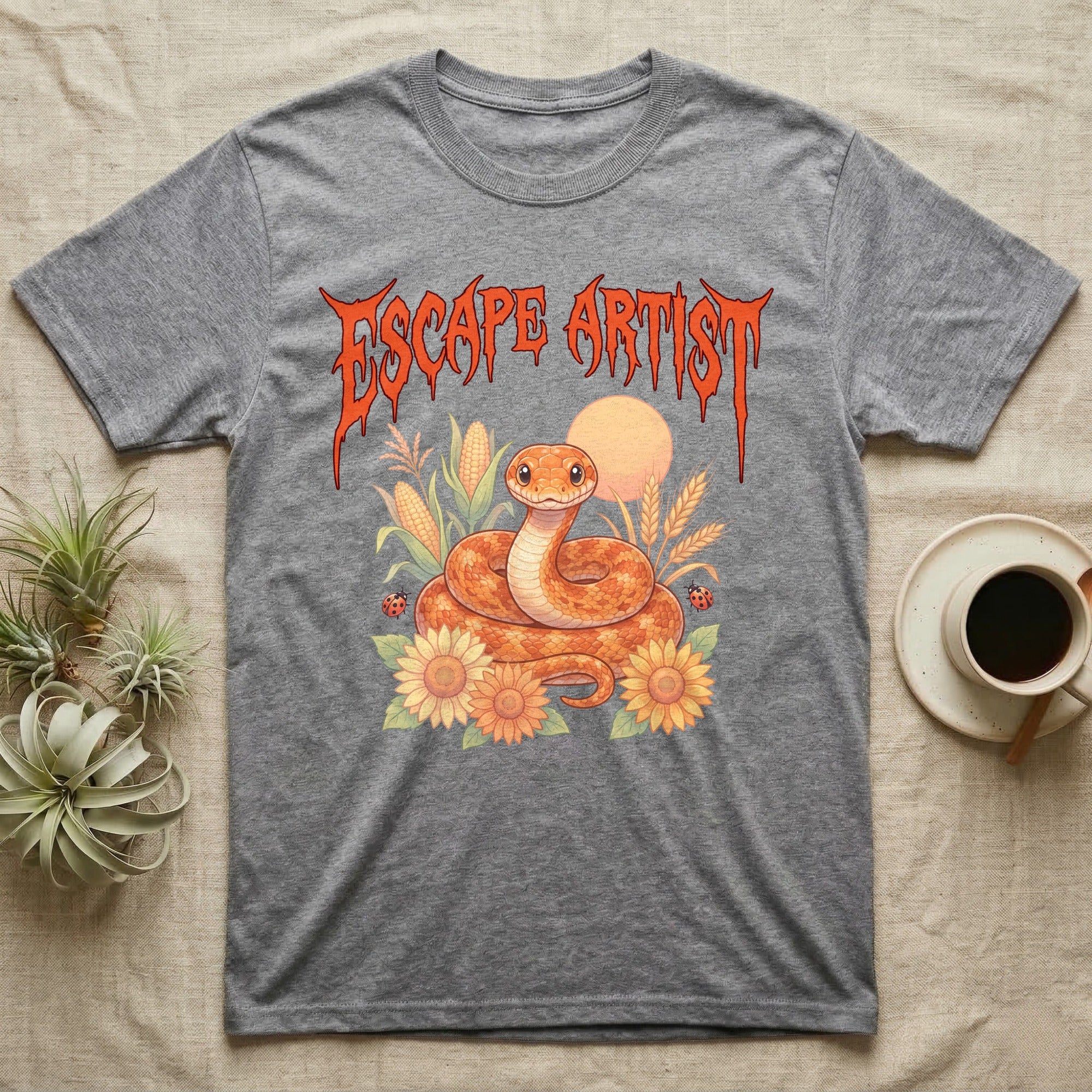Corn Snake Feral T-Shirt in Sport Grey — Orange corn snake coiled in a pastel cornfield scene under a spiky blood-orange metal wordmark reading ESCAPE ARTIST.