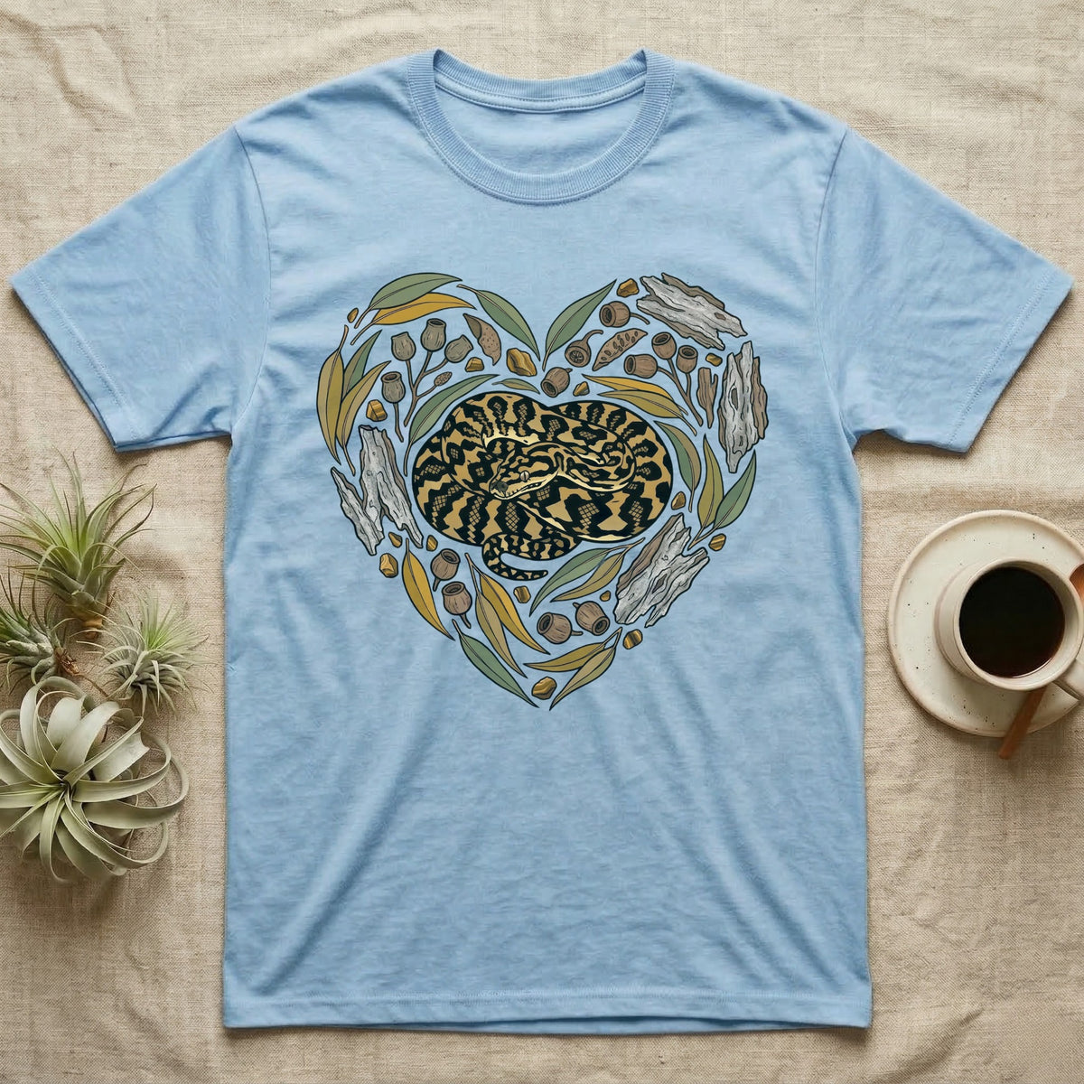 Blue t-shirt with a coiled snake and natural elements arranged in a heart shape.