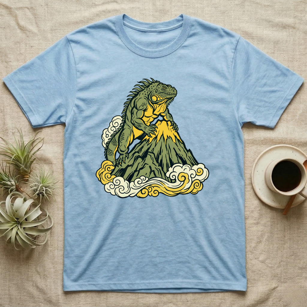 Light blue t-shirt featuring a green iguana on a mountain peak surrounded by clouds.
