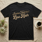 Tortoise Owner Retro T-Shirt in Black — Worn 1970s brush script reading Same Tortoise in tortoise-shell texture over Less Hair in warm sand, climbing a diagonal on charcoal grey