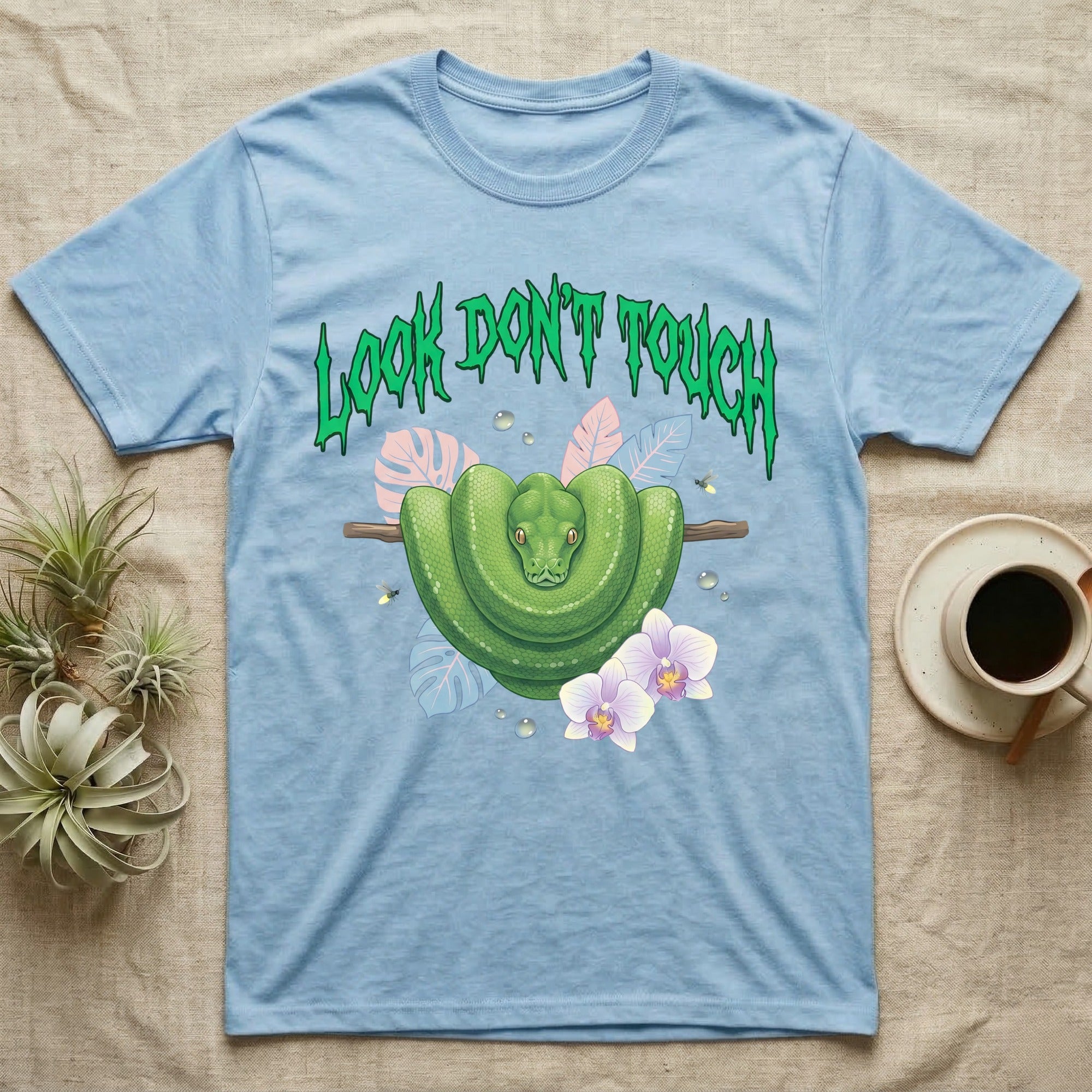 Green Tree Python Feral T-Shirt in Light Blue — Green tree python in a saddle coil on a branch under a jagged emerald metal "LOOK DON'T TOUCH" wordmark and orchids.