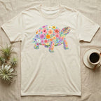 Box Turtle Mosaic T-Shirt in Natural — An eastern box turtle on a rising diagonal, its domed shell and legs built from painted watercolour flowers and leaves.