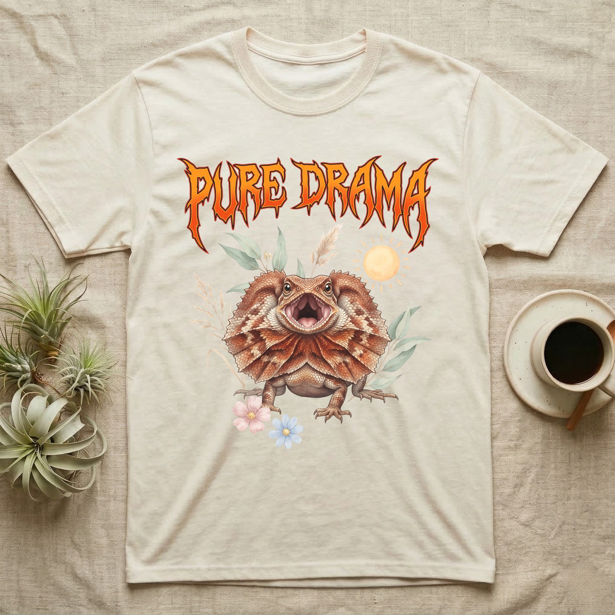 Frilled Dragon Feral T-Shirt in Natural — Frilled dragon with its neck frill flared and mouth gaping under a jagged fiery-orange metal "PURE DRAMA" wordmark.