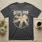 Macro badge illustration of a gecko's splayed foot with ribbed adhesive toe pads inside a distressed circular border, arched wordmark reading GECKO GRIP. — shown on a Dark Heather tee.