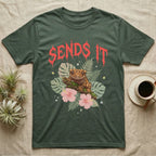 Crested Gecko Feral T-Shirt in Military Green — Crested gecko on a mossy branch in a pastel jungle scene under a spiky coral metal wordmark reading SENDS IT.