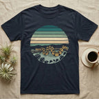 Ball Python Monstera T-Shirt in Navy — Ball python coiled through a striped rainforest circle window with monstera and pothos on a near-black tee