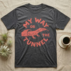 Ackie Monitor Tunnel T-Shirt in Dark Heather — Carved one-ink badge of an ackie monitor emerging from its sand tunnel, tongue out, ringed by the words MY WAY OR THE TUNNEL