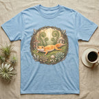 Light blue t-shirt with a watercolor illustration of a gecko surrounded by plants and mushrooms.