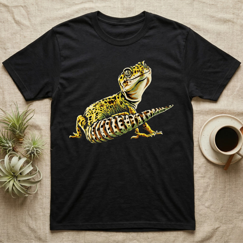 Illustration of a smiling leopard gecko with a plump curled spotted tail, bold vintage-comic ink outlines and halftone shading, graphic-only, no text. — shown on a Black tee.