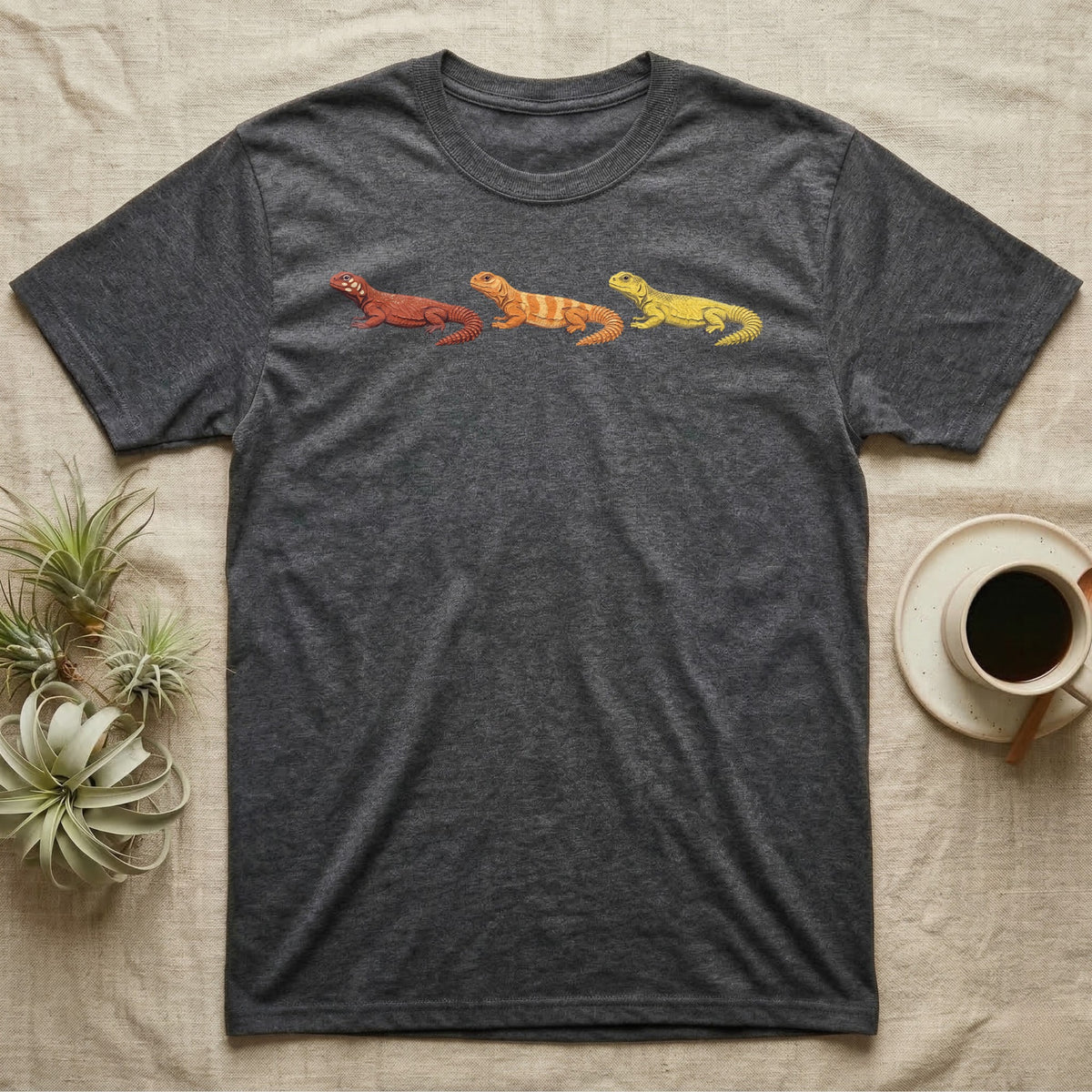 Uromastyx Colour Morph Trio T-Shirt in Dark Heather — Three uromastyx lizards in a row, painted in thick raised relief — brick red, tangerine orange and lemon yellow morphs.