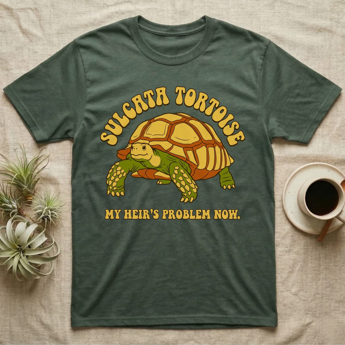 Green t-shirt with a tortoise graphic and text "SULCATA TORTOISE MY HEIR'S PROBLEM NOW."