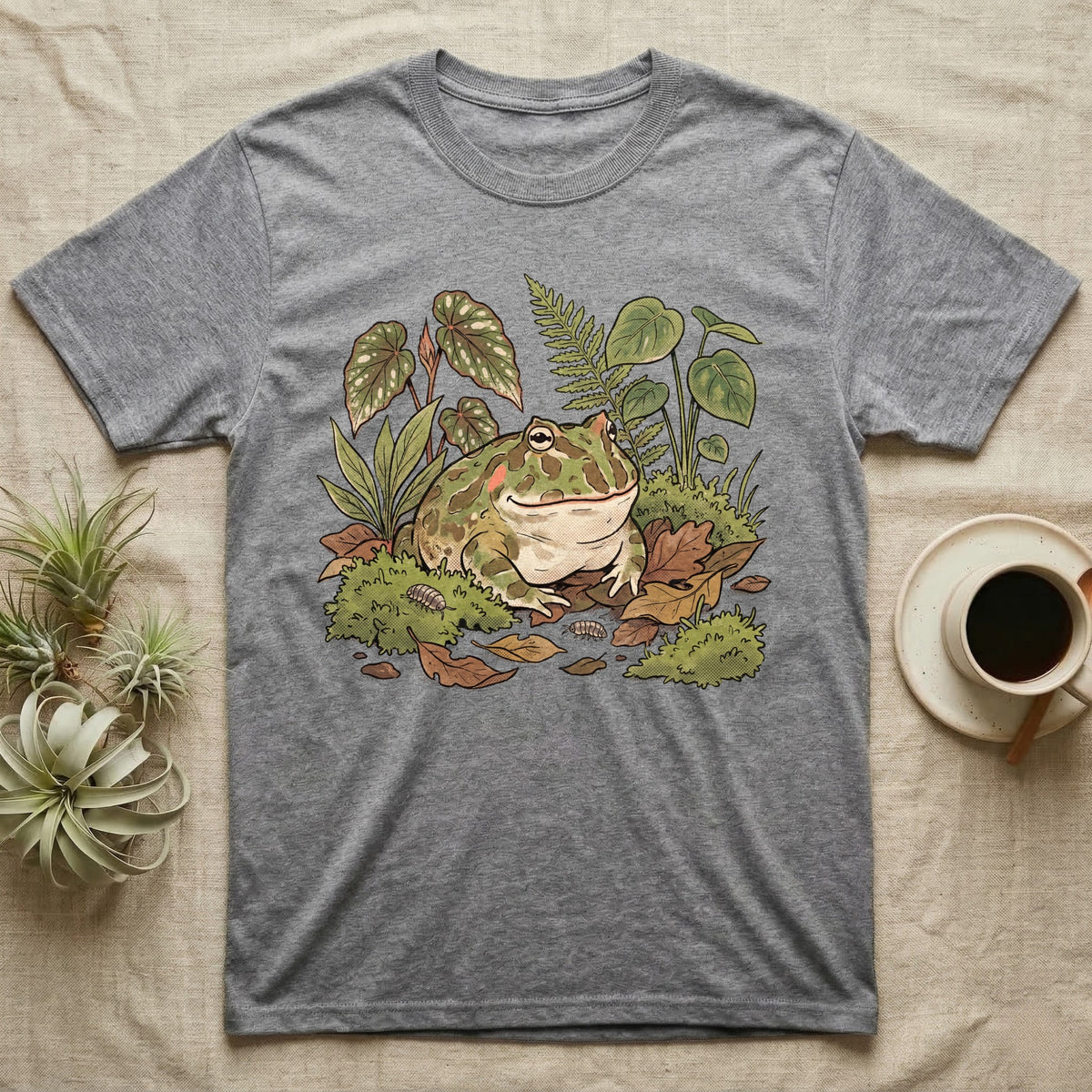 Bioactive Pacman Frog T-Shirt in Sport Grey — Warm botanical illustration of a content pacman frog half-buried in a lush bioactive habitat of moss and leaf litter.