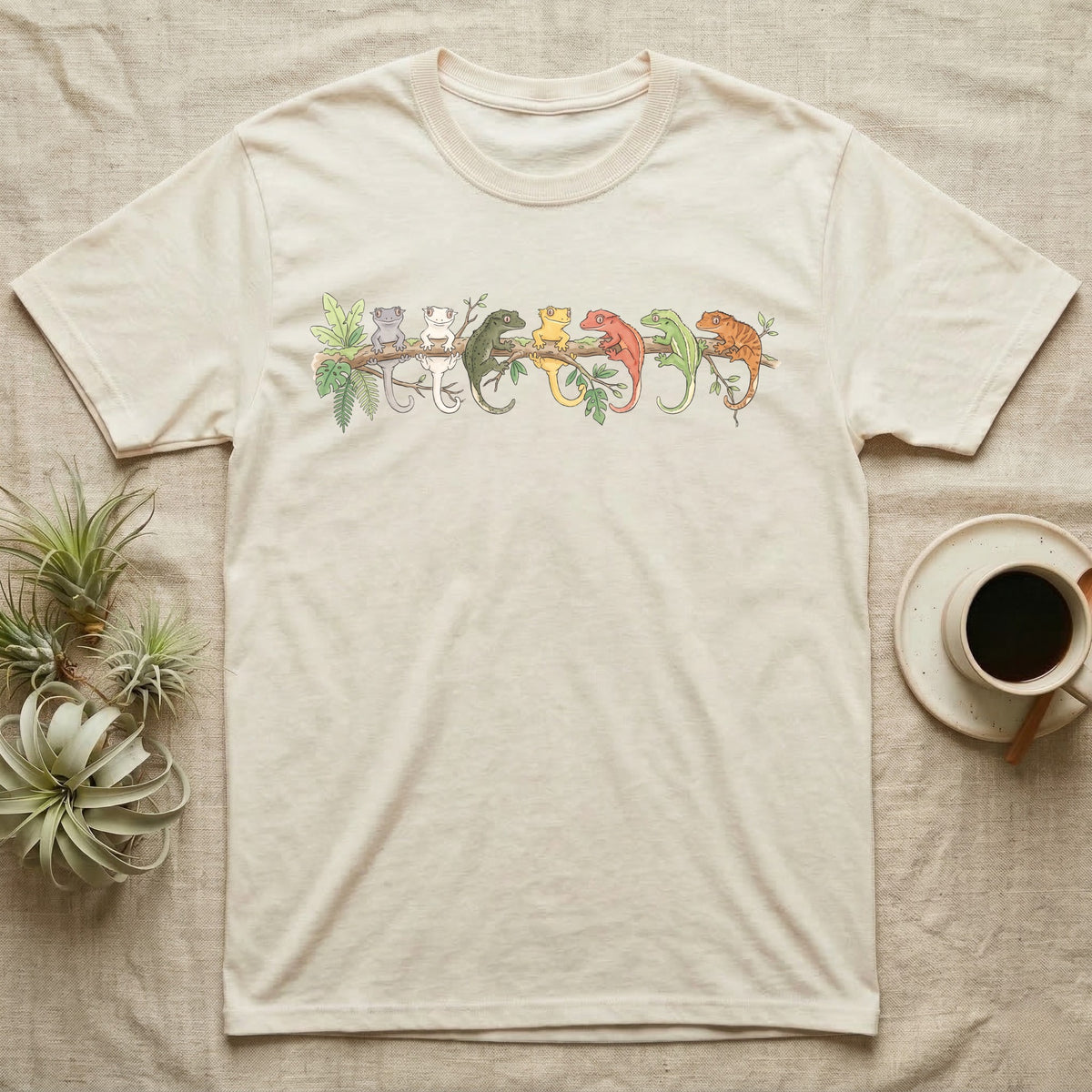 Crested Gecko Canopy Crew T-Shirt in Natural — Watercolor illustration of seven crested gecko colour morphs perched on a branch, dark grey T-shirt design.