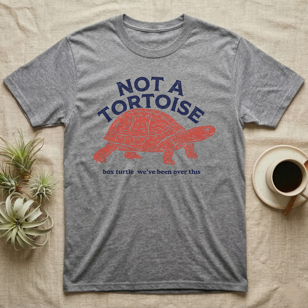 Box Turtle Not A Tortoise T-Shirt in Sport Grey — Two-ink worn stamp print of an eastern box turtle striding right on stumpy clawed legs beneath the arched words NOT A TORTOISE.
