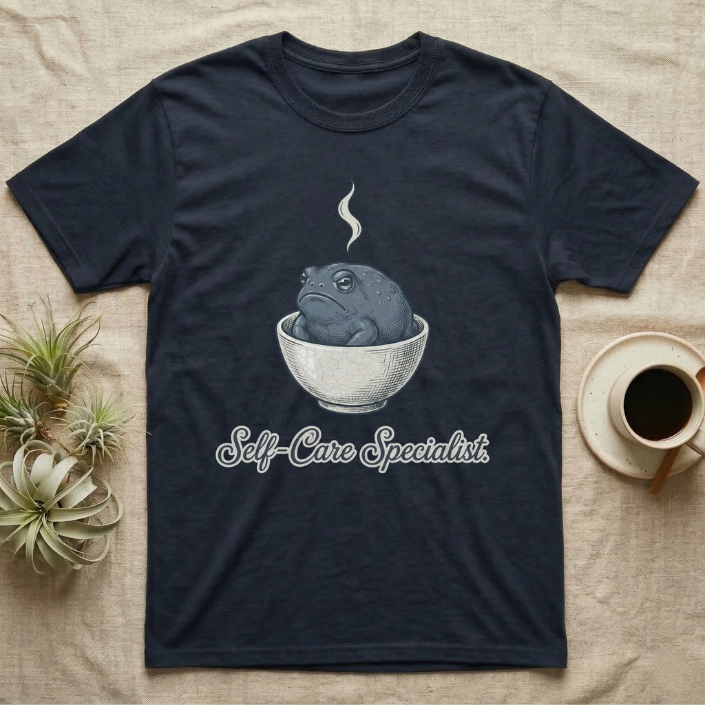 Dark t-shirt with a gray frog in a bowl and "Self-Care Specialist" text.
