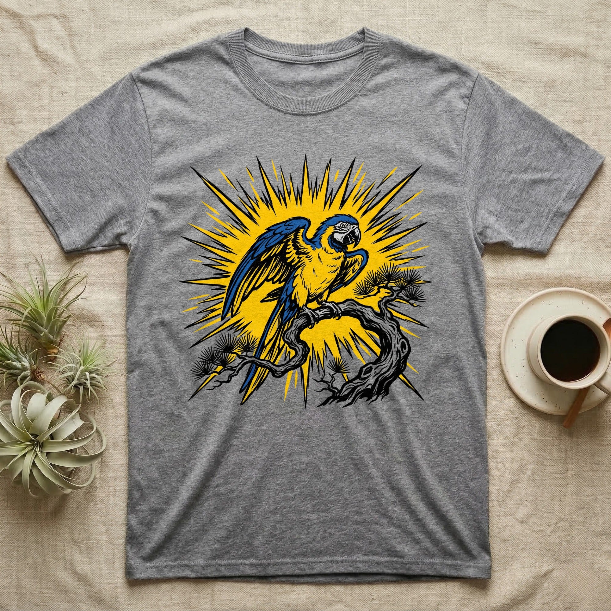 Grey t-shirt featuring a blue and yellow parrot perched on a branch with a sunburst design.