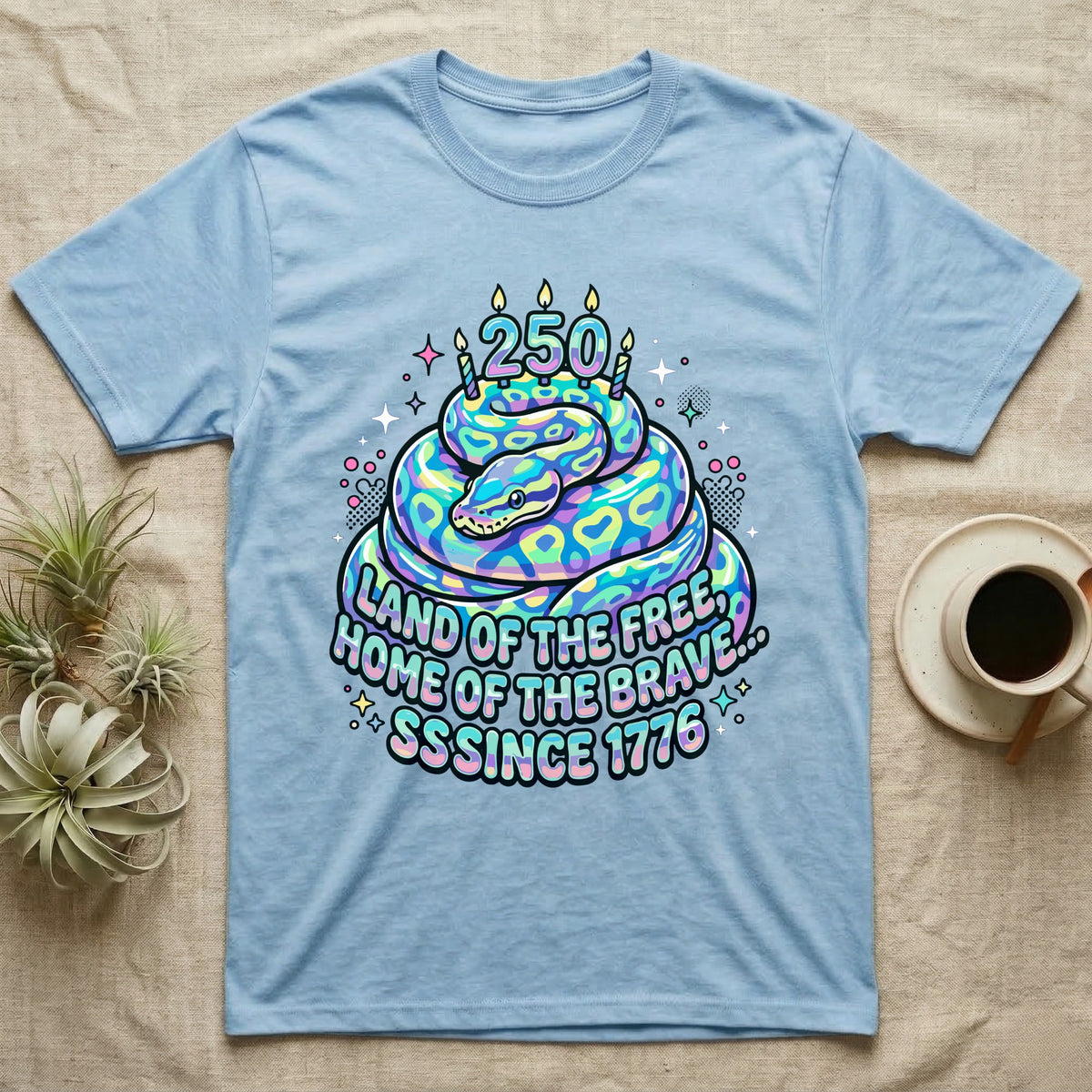 Ball Python Birthday Cake T-Shirt in Light Blue — Y2K pastel ball python coiled as a birthday cake with 250 candles and bubble text Land of the Free, Sssince 1776.