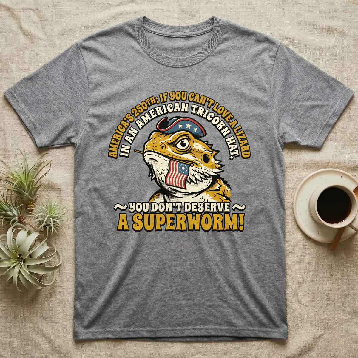 Bearded Dragon Tricorn Tee in Sport Grey — Bold woodcut tee of a bearded dragon in a colonial tricorn hat, gold and cream text reading You Don't Deserve A Superworm, on black.