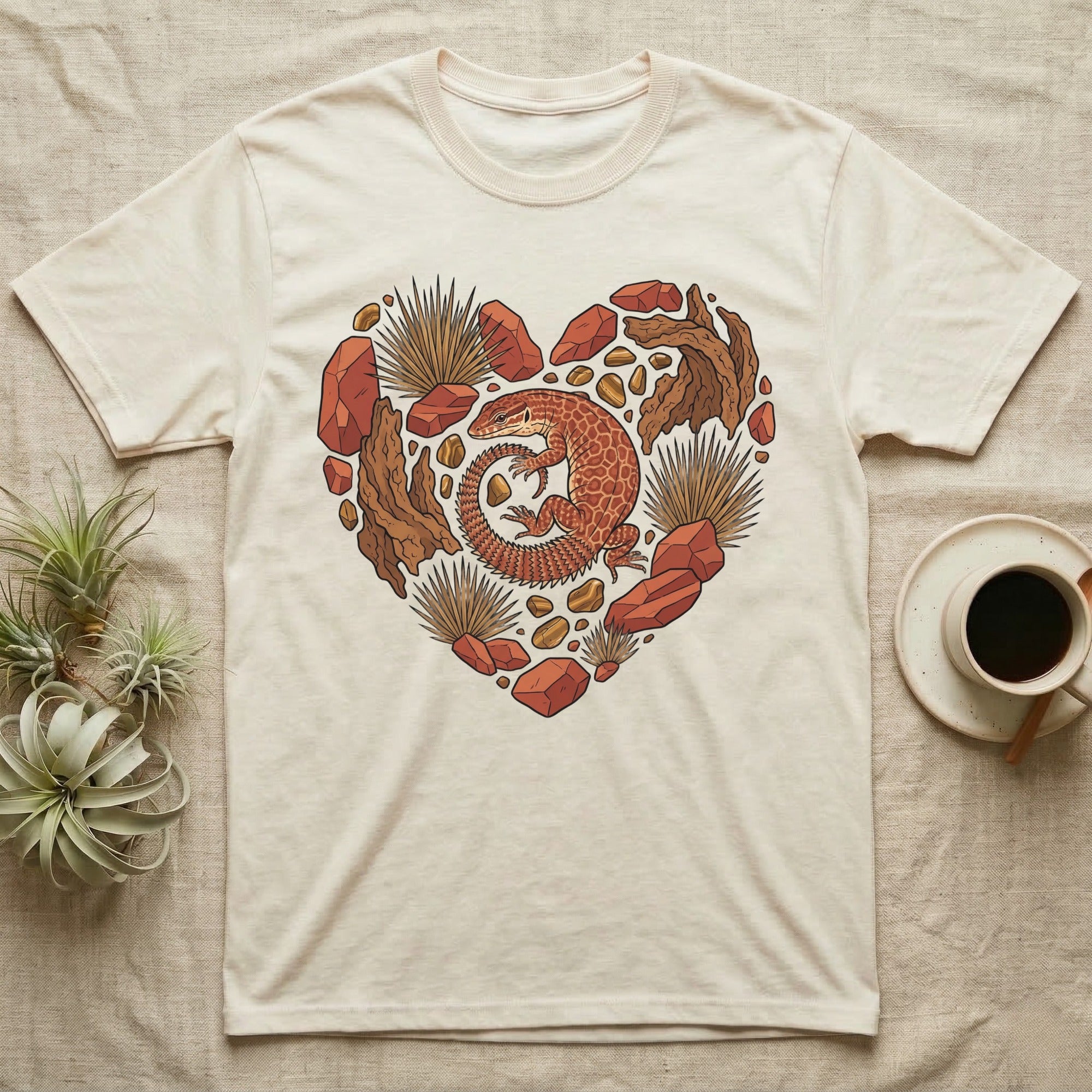Heart-shaped design with lizard, rocks, and plants on a cream t-shirt.