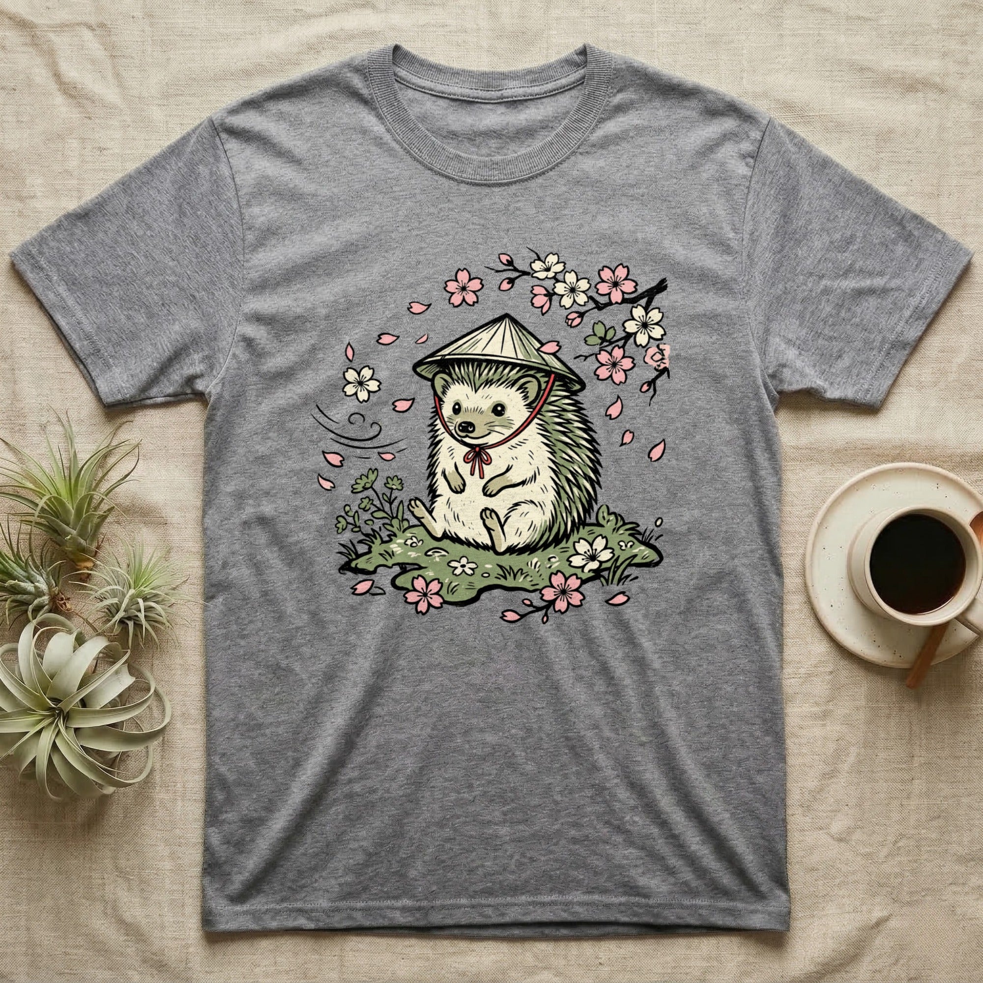 Grey t-shirt with a cartoon hedgehog wearing a conical hat and surrounded by cherry blossoms.