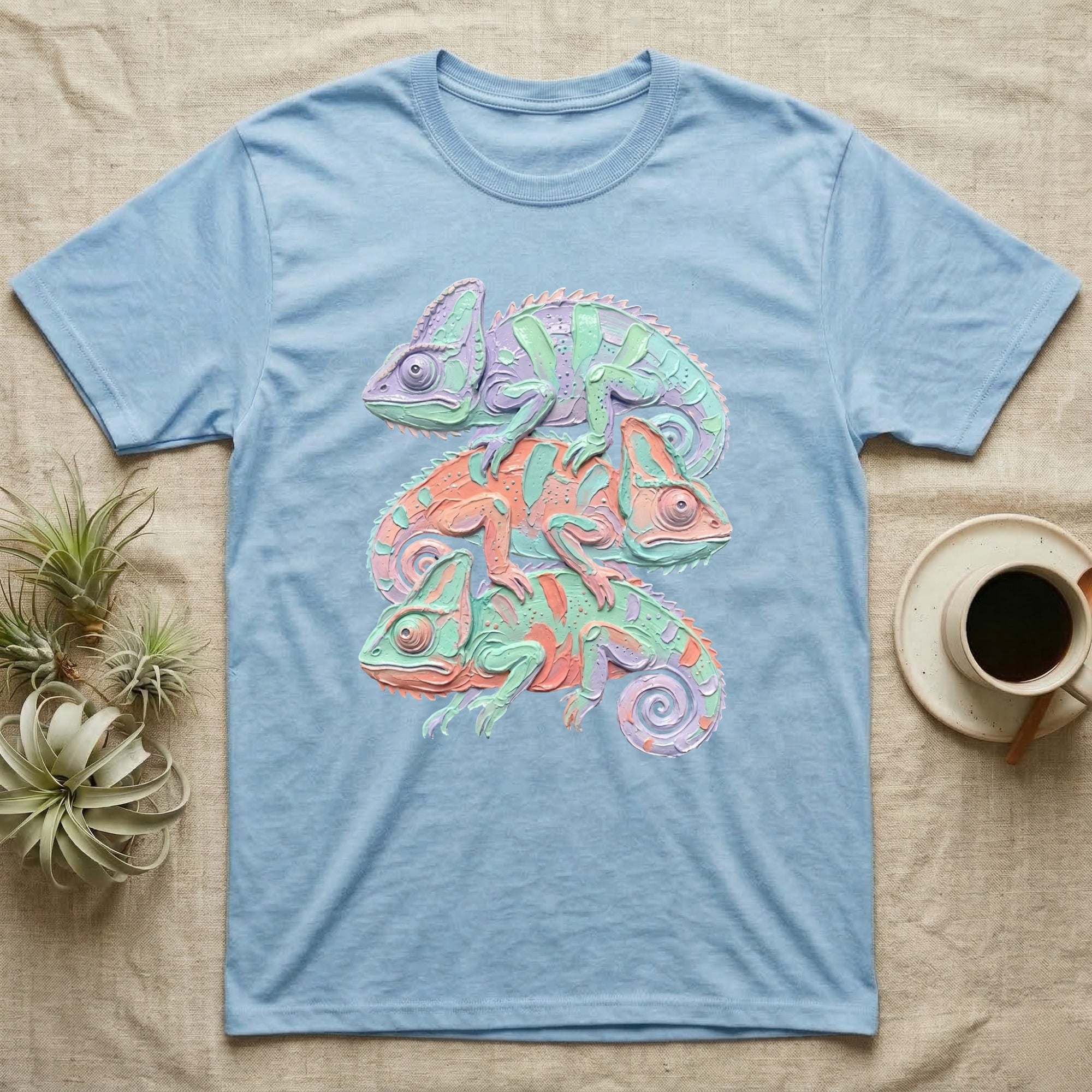 Stack of three colorful chameleons printed on a light blue t-shirt.