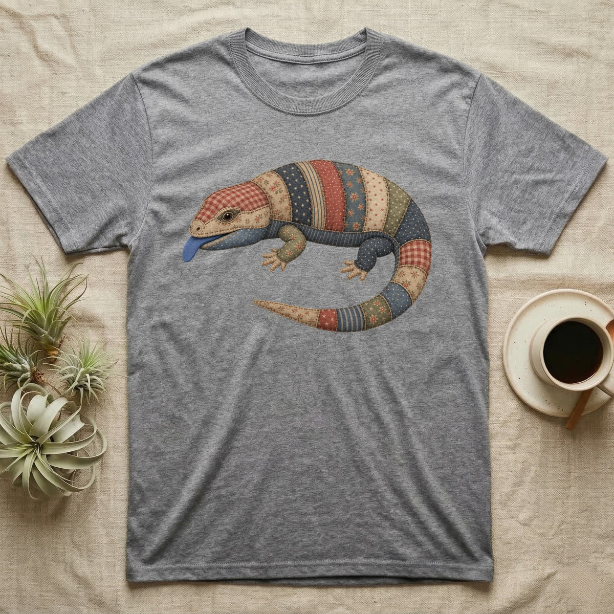 Grey t-shirt with a quilted lizard design and a blue tongue.