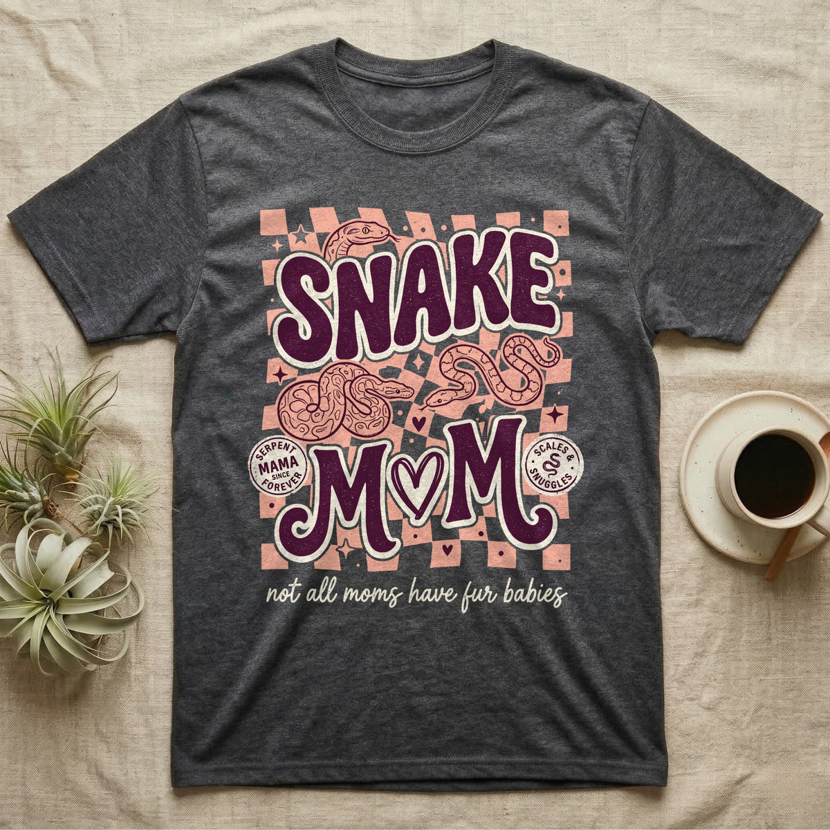Dark grey t-shirt with "Snake Mom" text and coiled snakes, with checkered background.