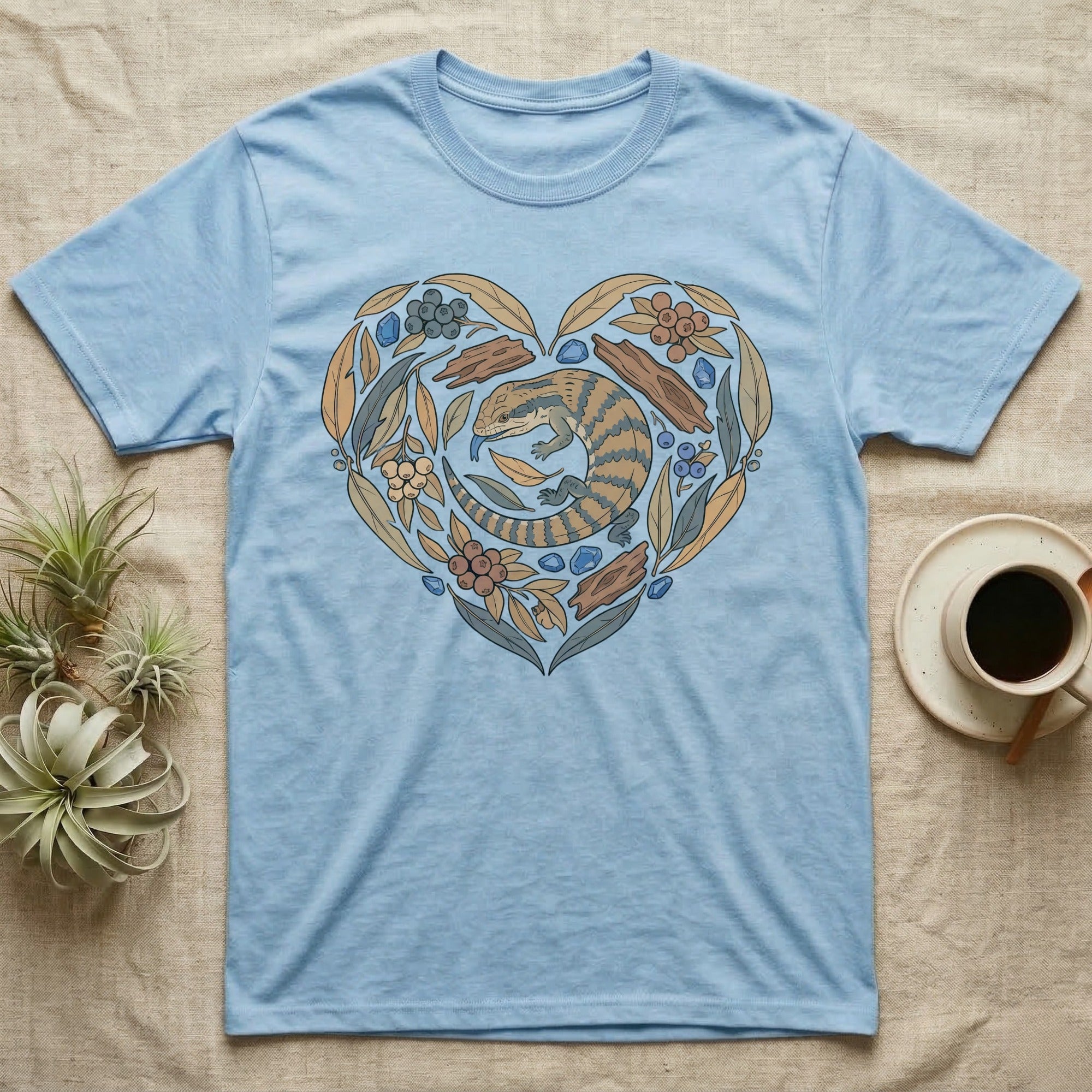 Light blue t-shirt with a heart-shaped design of a lizard and floral elements.