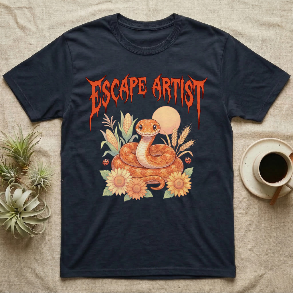 Corn Snake Feral T-Shirt in Navy — Orange corn snake coiled in a pastel cornfield scene under a spiky blood-orange metal wordmark reading ESCAPE ARTIST.
