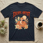 Corn Snake Feral T-Shirt in Navy — Orange corn snake coiled in a pastel cornfield scene under a spiky blood-orange metal wordmark reading ESCAPE ARTIST.