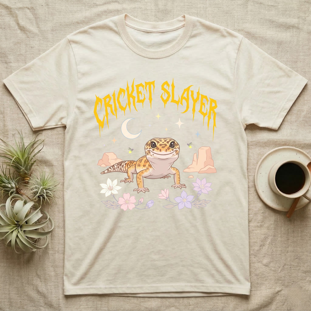 Leopard Gecko Feral T-Shirt in Natural — Smiling leopard gecko in a pastel desert-night scene under a spiky golden metal wordmark reading CRICKET SLAYER.